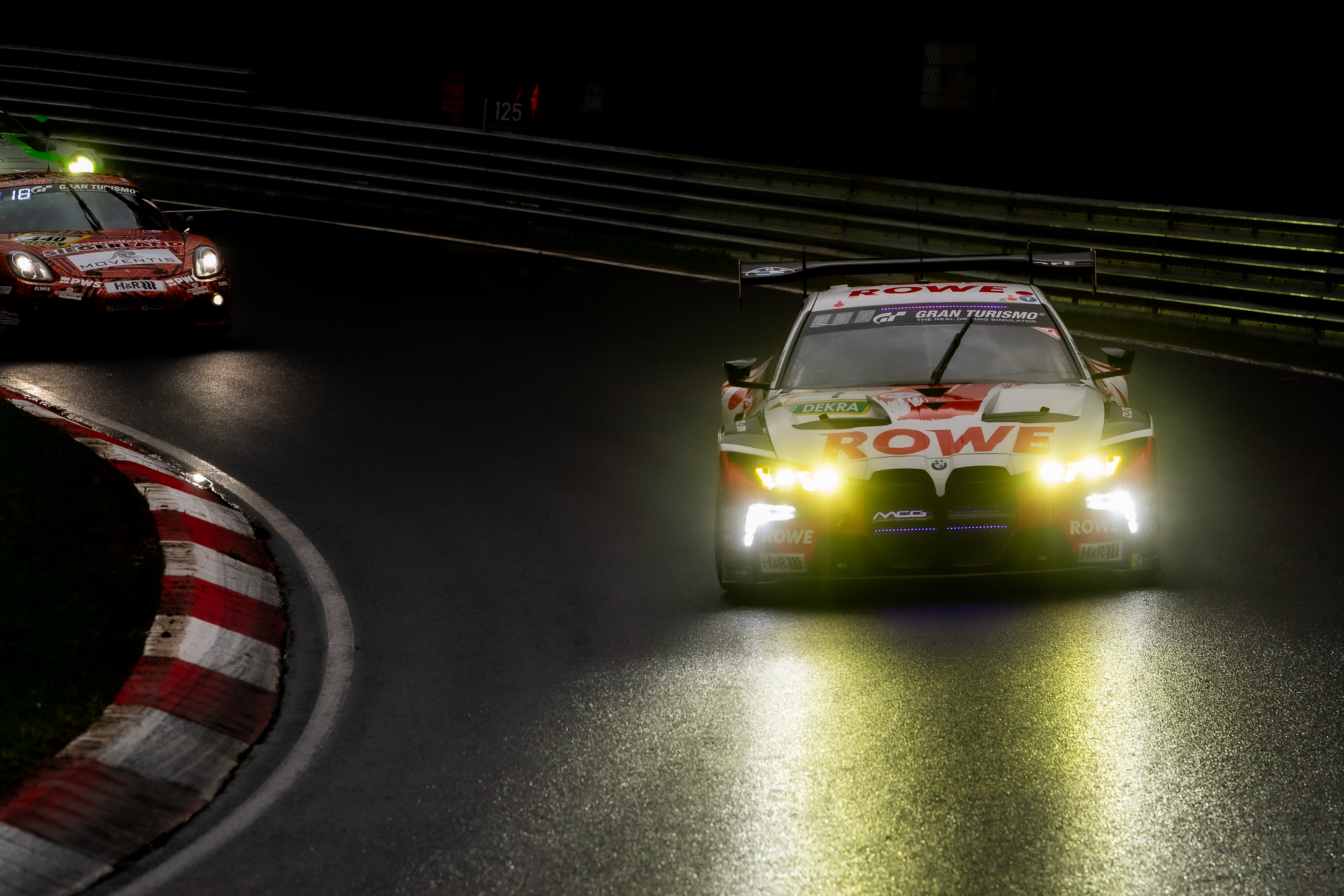 ROWE RACING SP 9 PRO (IGTC) (#1) mit den Fahrern Augusto Farfus (BRA), Raffaele Marciello (SUI), Jordan Pepper (RSA), Kelvin van der Linde (RSA). Der BMW M4 GT3 Evo (#1) im ROWE Racing Design fährt mit eingeschalteten gelben Scheinwerfern auf nasser Strecke eine Kurve, dahinter ein zweites Fahrzeug mit roten Lichtern bei wechselhaftem Wetter im ADAC RAVENOL 24h Nürburgring GE Qualifying 2. Nürburgring, 14.05.2026. Nürburgring, 14.05.2026
