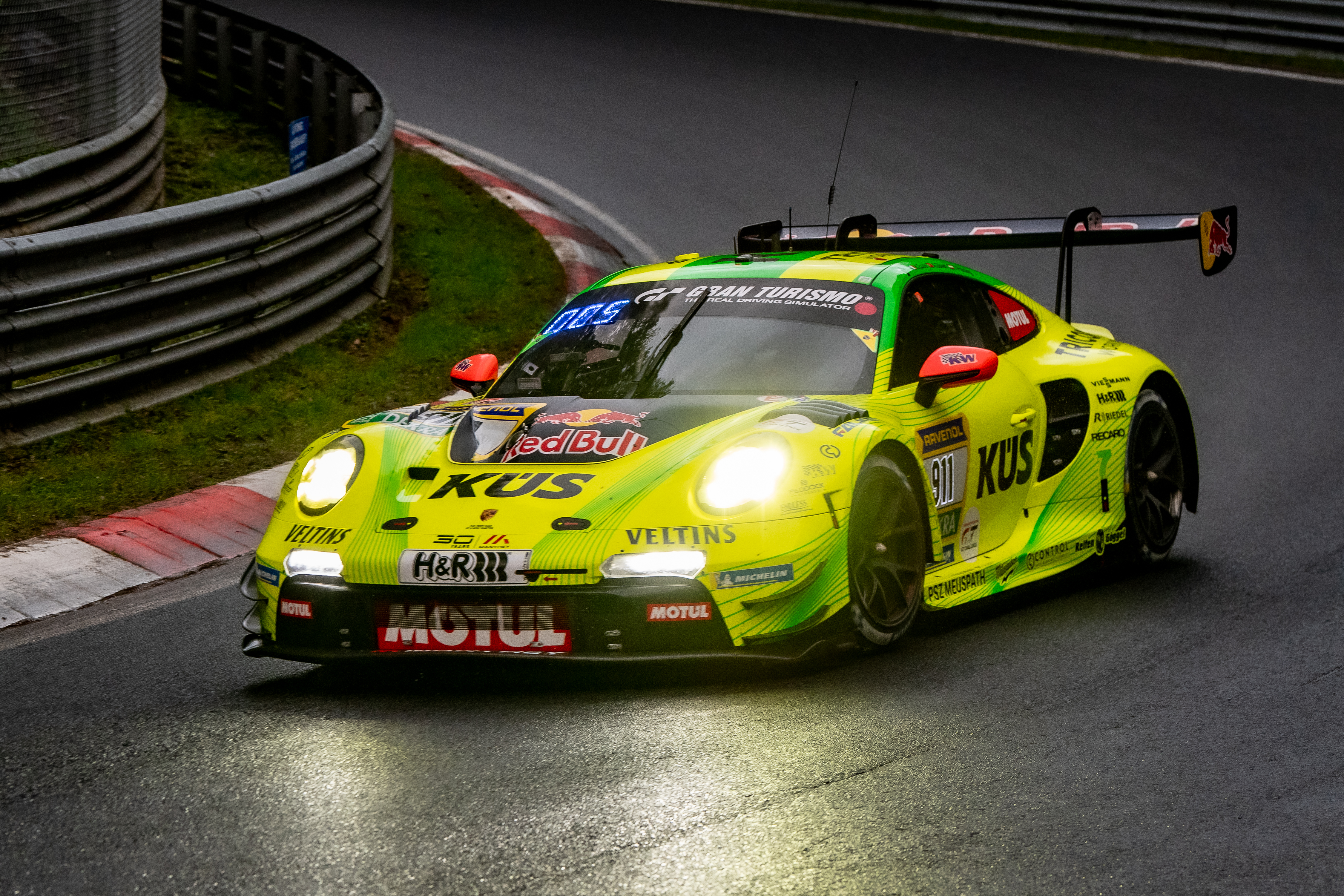 Manthey SP 9 PRO (IGTC) (#911) mit den Fahrern Kevin Estre chst (FRA), Ayhancan Güven (TUR), Thomas Preining (AUT). Ein gelb-grüner Porsche 911 GT3 R (#911) mit KÜS und Red Bull Werbung fährt bei nasser Fahrbahn Kurve auf der Nürburgring Rennstrecke im Rahmen des ADAC RAVENOL 24h Nürburgring GE Qualifying 2. Nürburgring, 14.05.2026. Nürburgring, 14.05.2026