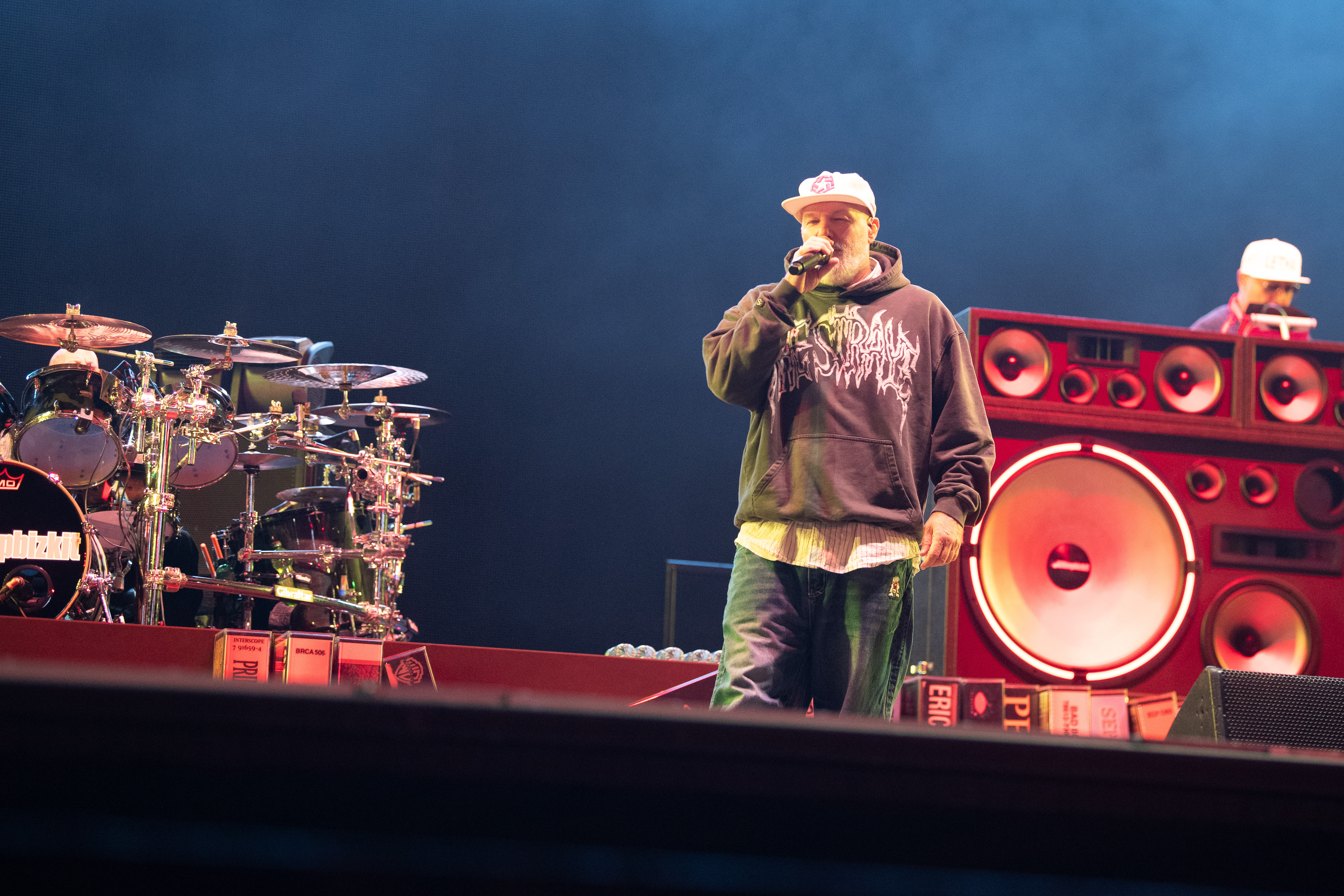 Fred Durst Sänger von Limp Bizkit mit weißer Cap und dunklem Hoodie auf der Bühne vor Mikrofon beim Rock am Ring Festival, daneben John Otto Schlagzeuger, Bühne mit roten Boxen.
Nürburgring, 06. Juni 2026. Foto: Alexander Franz