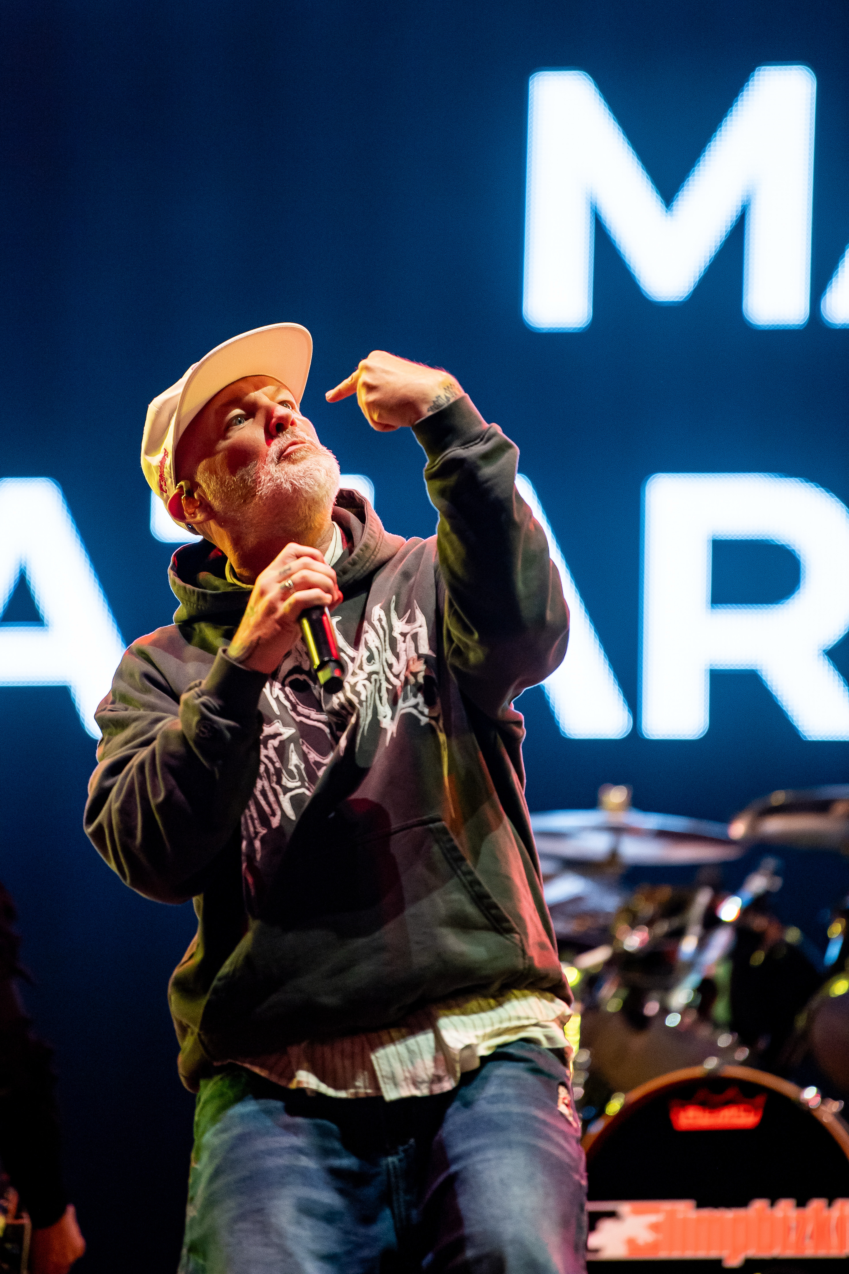 Fred Durst Sänger von Limp Bizkit mit weißem Bart und Basecap, schwarzem Hoodie, der mit der rechten Hand auf seinen Kopf zeigt, vor Leuchtbuchstaben auf der Bühne beim Rock am Ring Festival.
Nürburgring, 06. Juni 2026. Foto: Alexander Franz