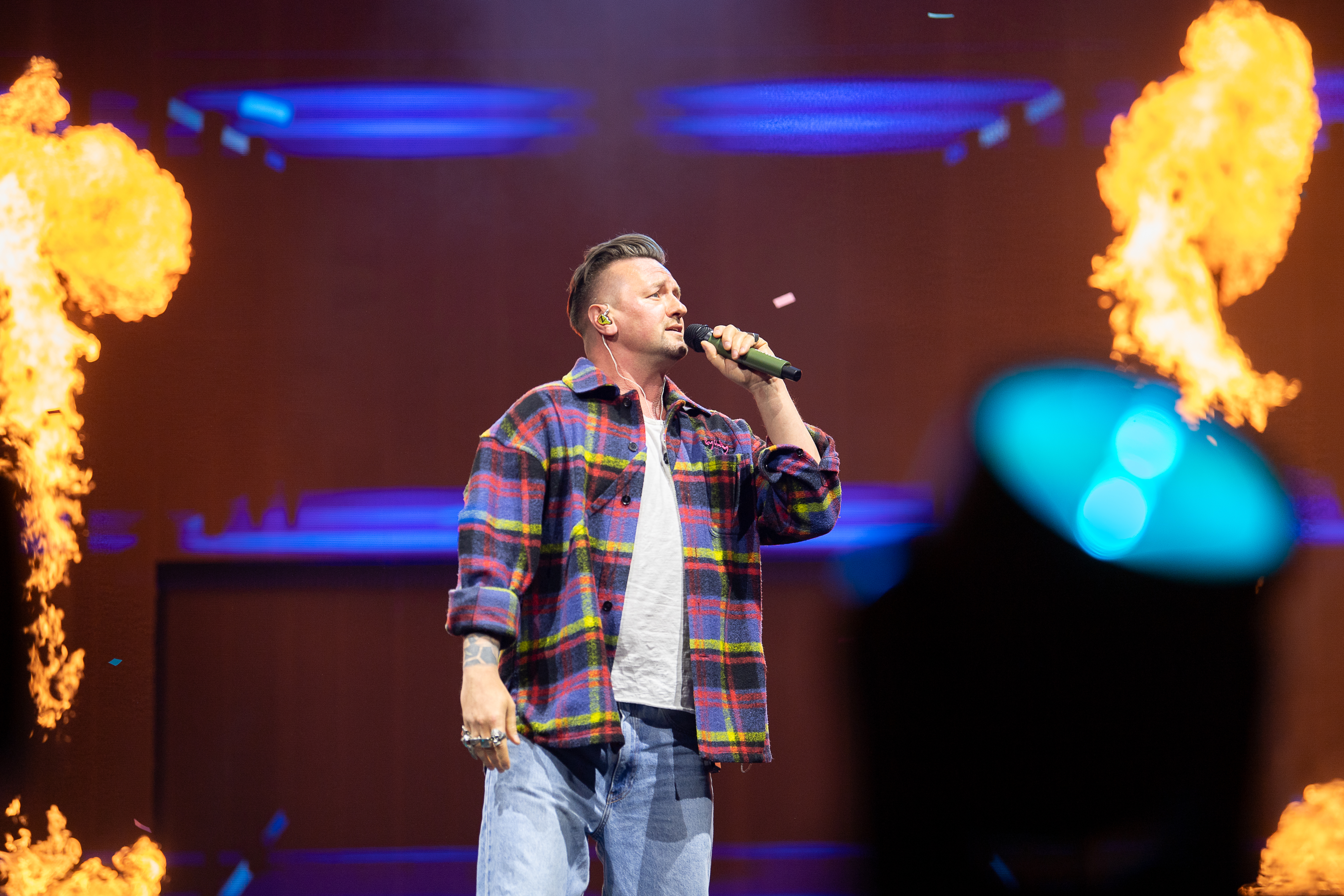Ben Zucker steht mit Mikrofon auf der Bühne und wird von Feuer-Effekten umgeben während der Schlagernacht des Jahres 2026. Köln, Lanxess Arena