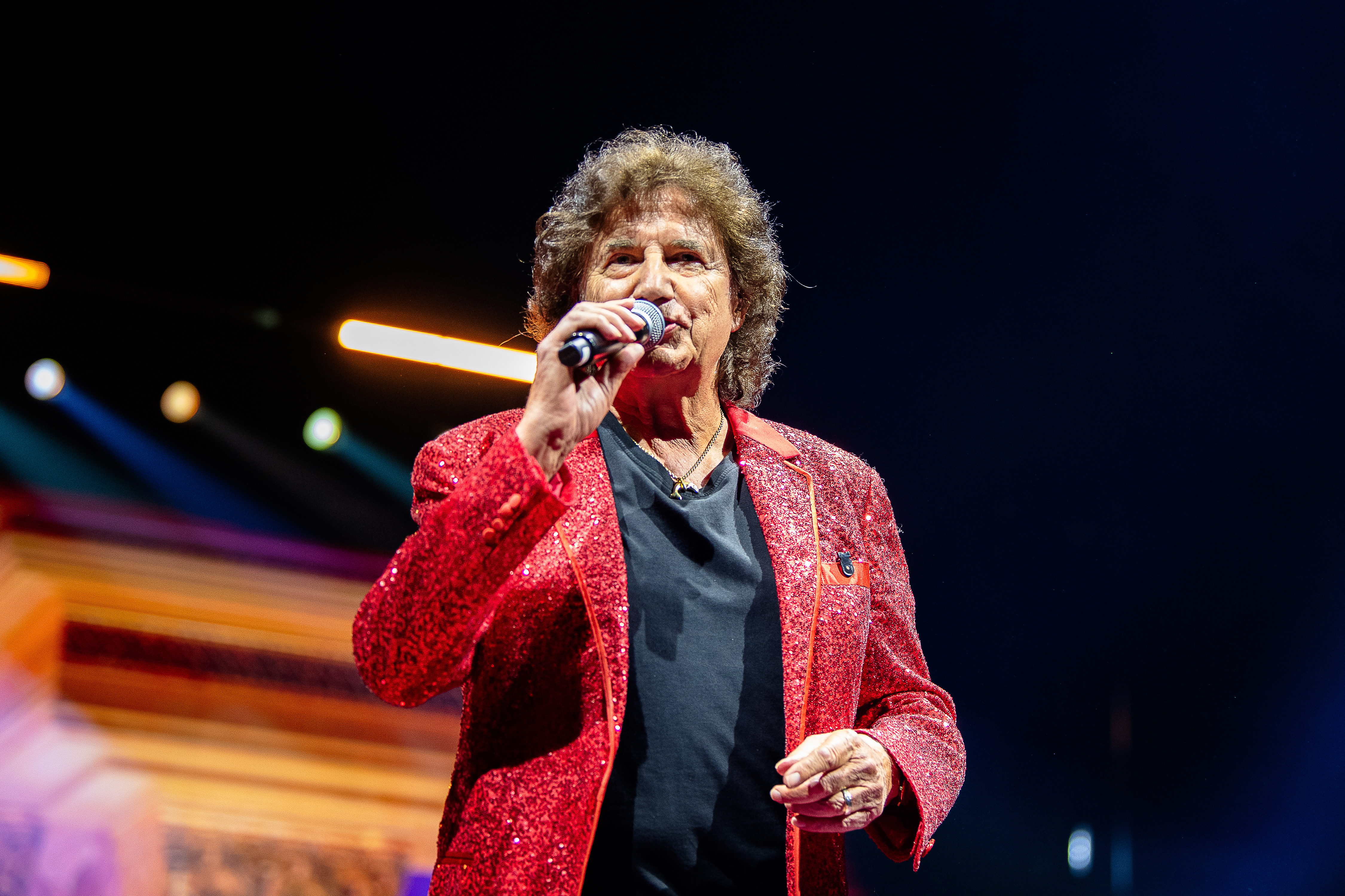 Olaf der Flipper im roten Glitzerjackett singt mit Mikrofon auf der Bühne bei der Schlagernacht des Jahres in der LANXESS arena in Köln.
