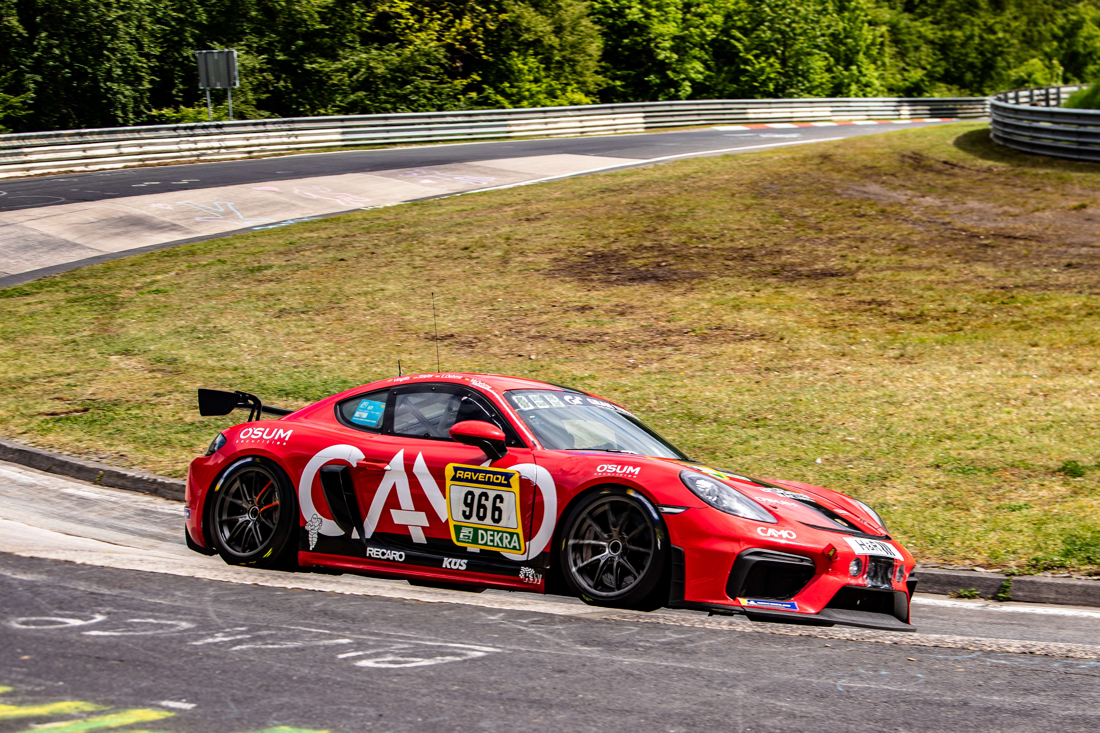 Ein roter Porsche 911 GT3 R Evo fährt eine Kurve auf der Rennstrecke am Nürburgring.